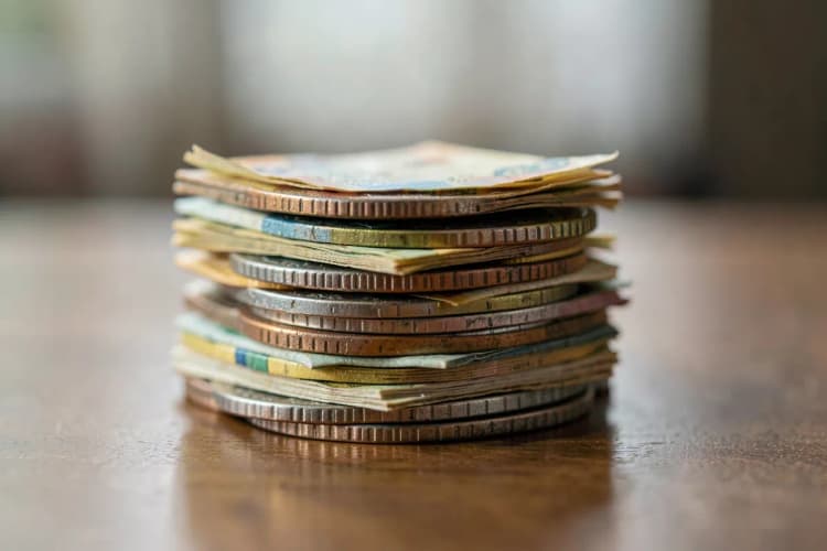 Uma pilha de moedas e notas de dinheiro em cima de uma mesa