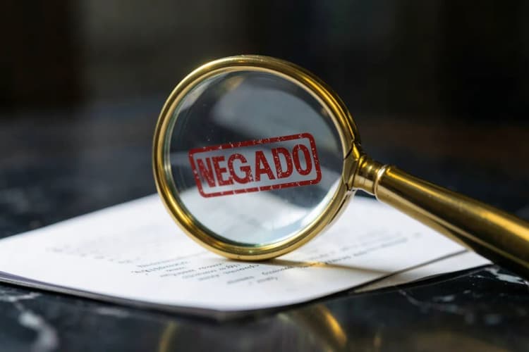 Uma lupa examinando um documento com um selo de "negado".