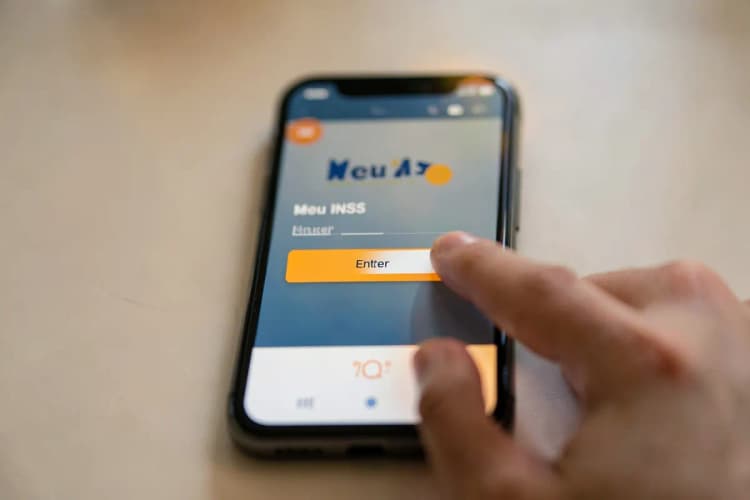 Um smartphone exibindo a tela de login do aplicativo Meu INSS com um dedo pressionando o botão "Entrar".
