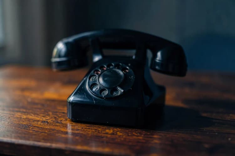 Um telefone antigo em cima de uma mesa de madeira escura, com um fundo desfocado.