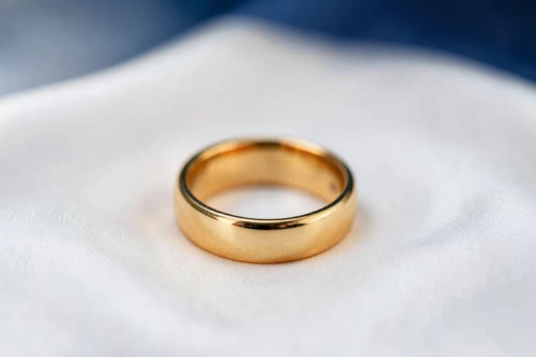 Uma aliança de ouro sobre um fundo de seda branco.